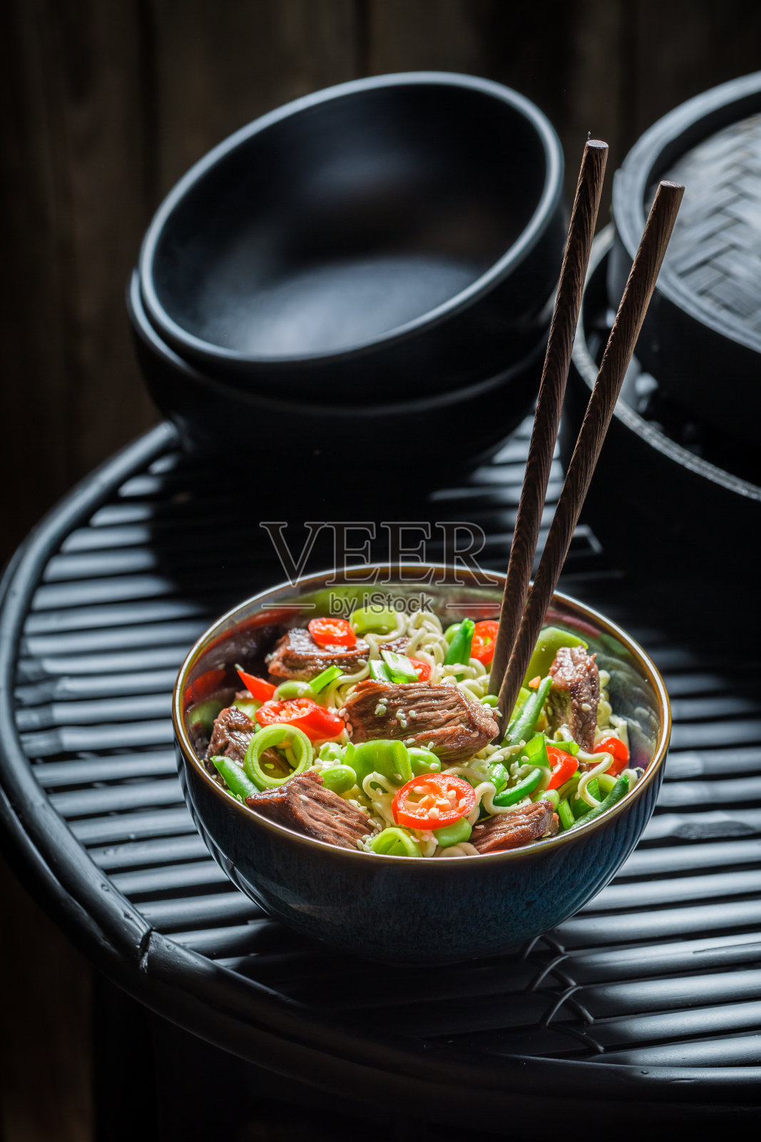 热亚洲面条，蔬菜和牛肉在黑色的桌子上照片摄影图片