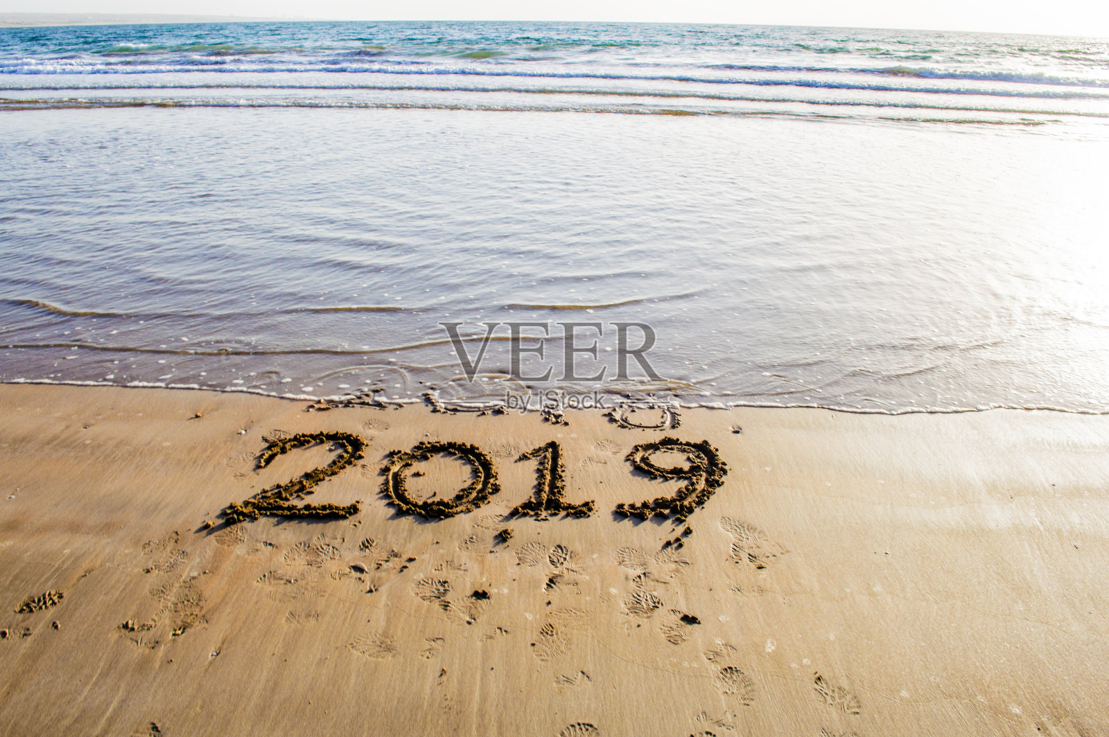 在海边的沙滩上写2019年新年快乐。即将到来的2019年和即将离开的2018年的抽象背景照片照片摄影图片