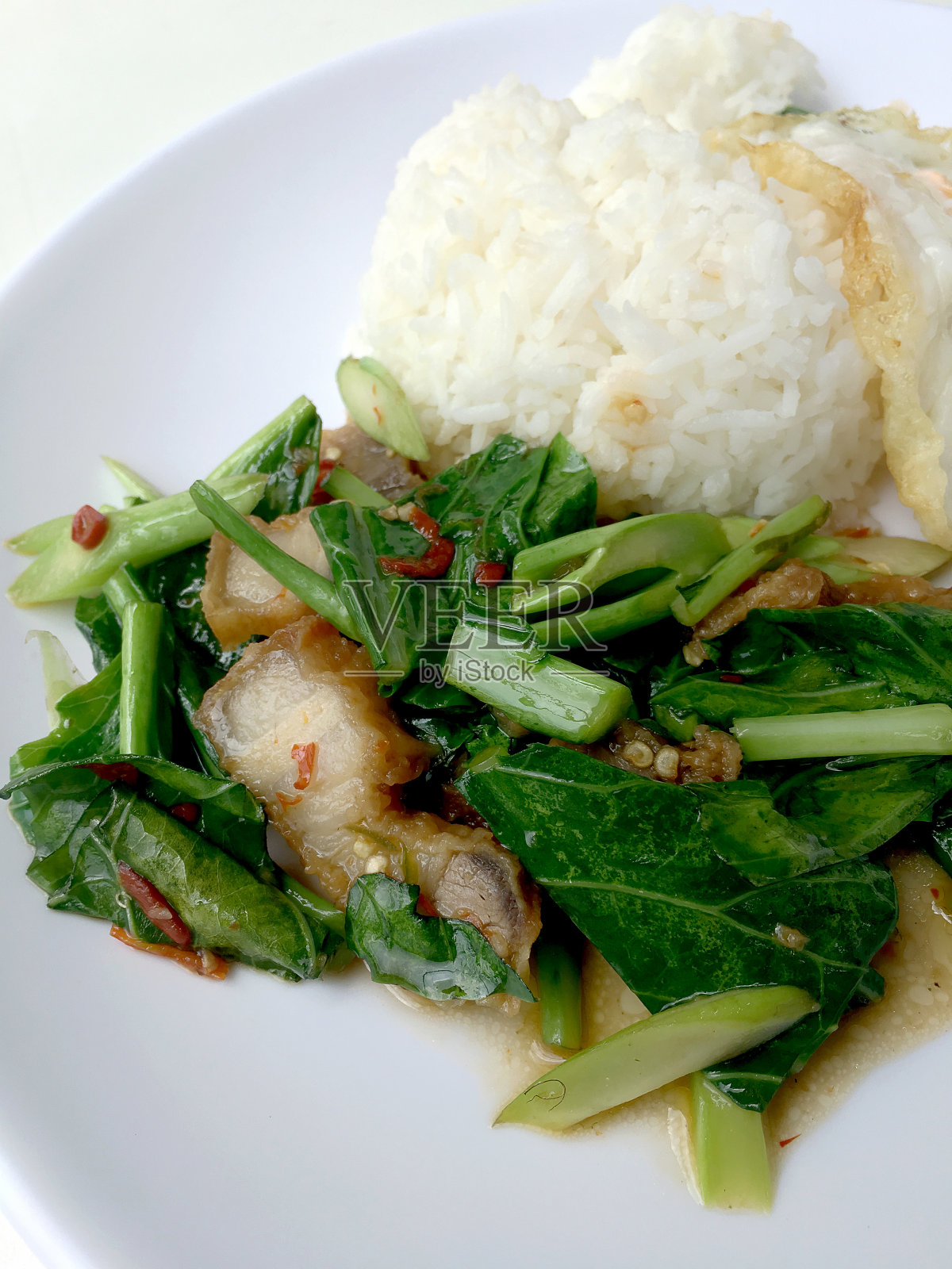 炒凯兰和香酥猪肉，炒白饭，白底白饭。泰国风格的食物。照片摄影图片