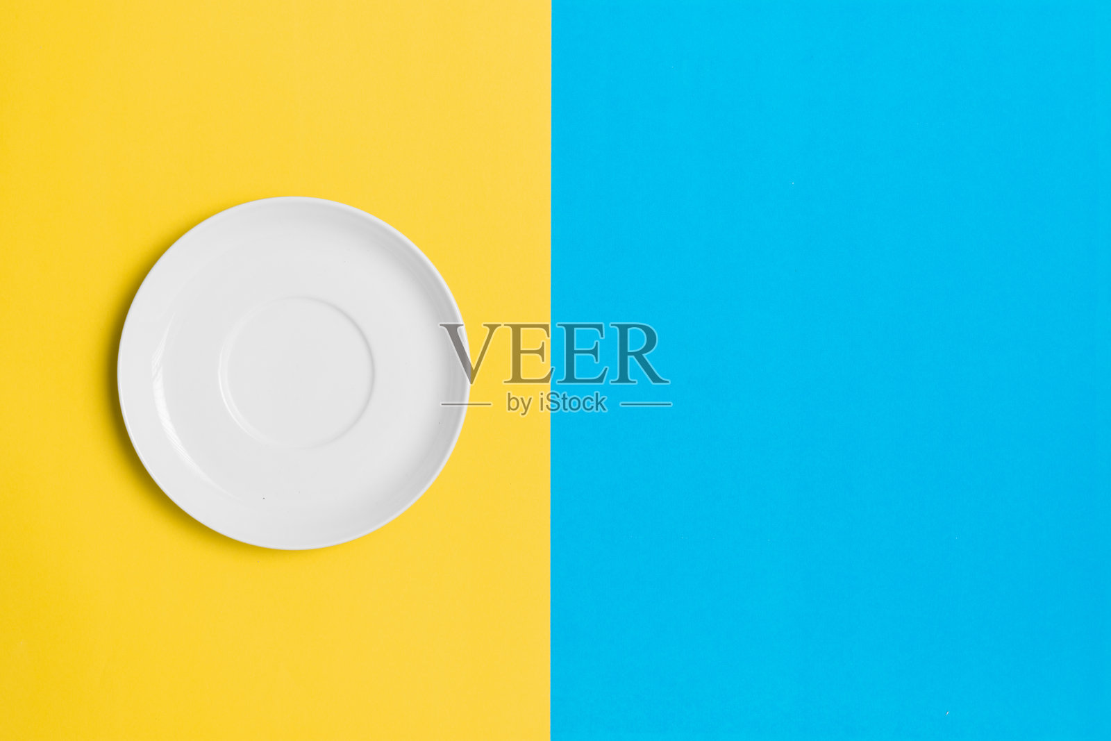 空盘子在对比的黄色和蓝色背景。照片摄影图片