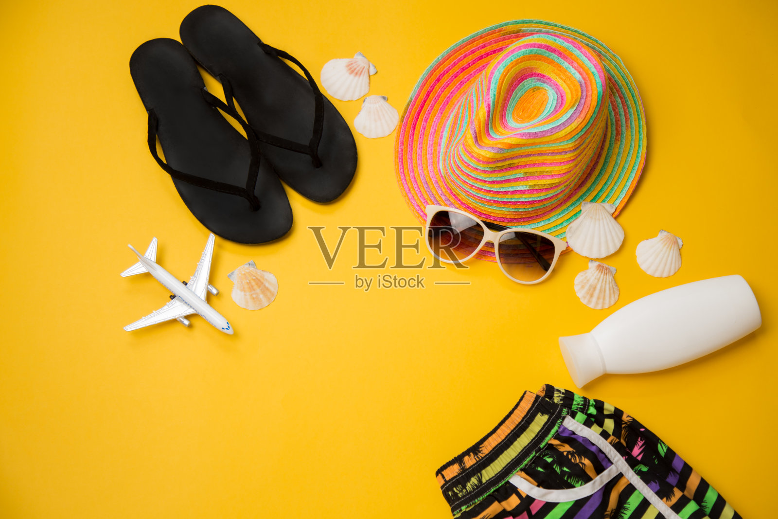 拖鞋，帽子，黄色背景的太阳镜。飞机旅行浓缩的照片摄影图片