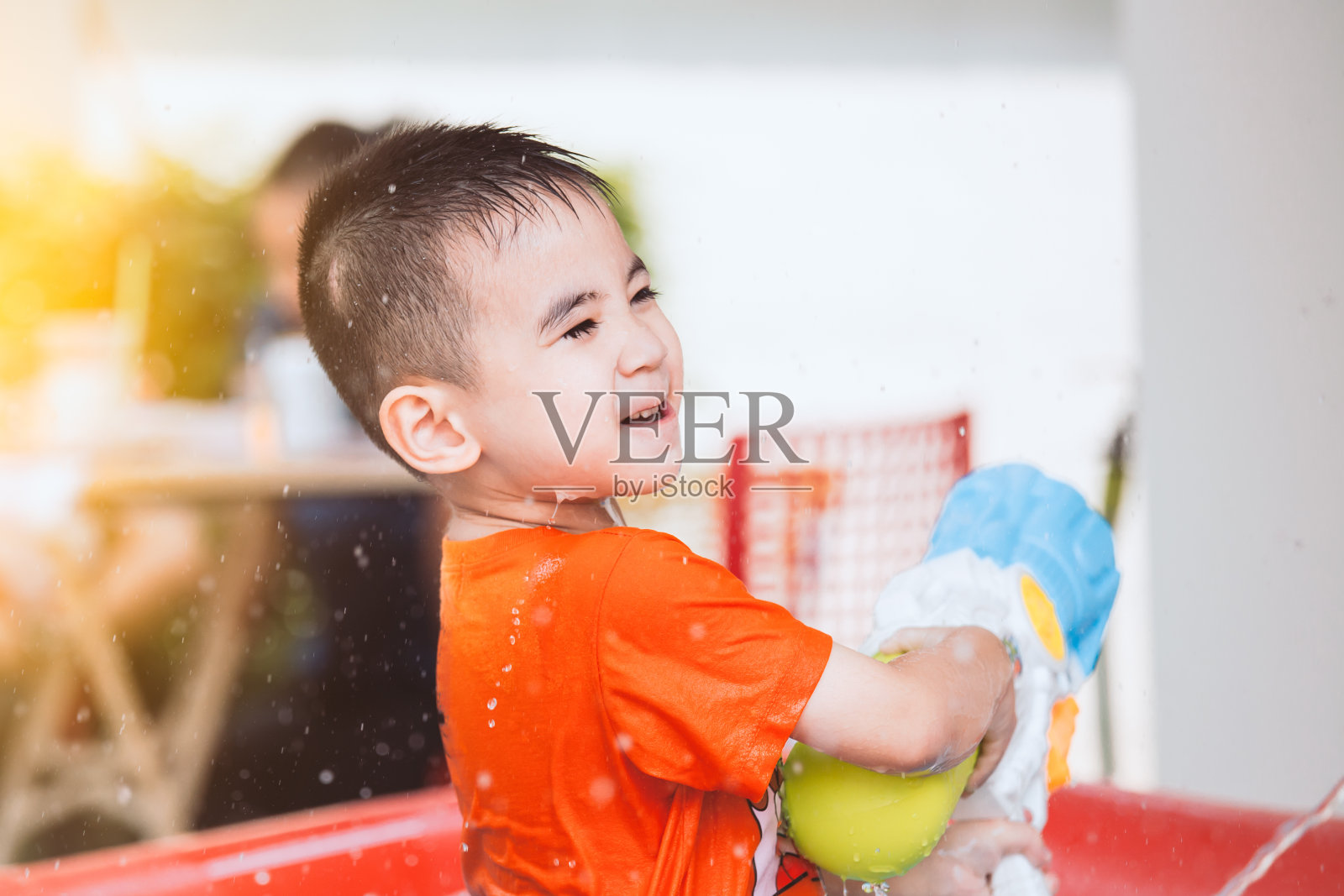 快乐的亚洲小男孩玩水与水枪和泰国泼水节的乐趣照片摄影图片