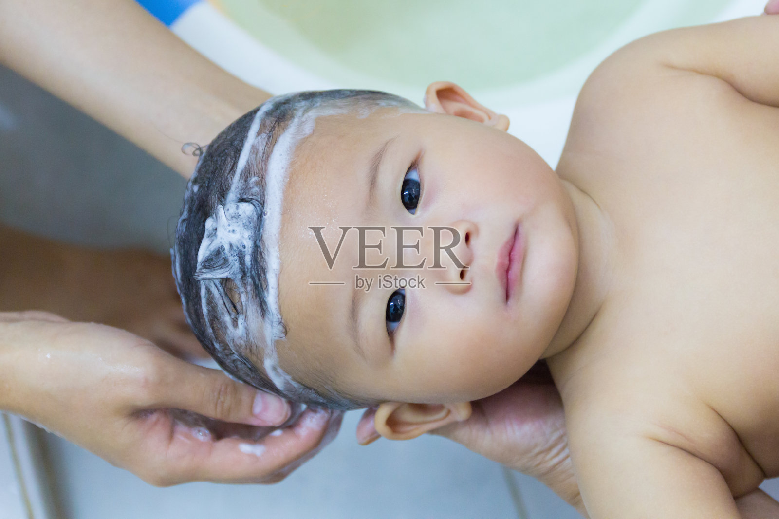 亚洲可爱宝宝八个月洗澡洗头。照片摄影图片