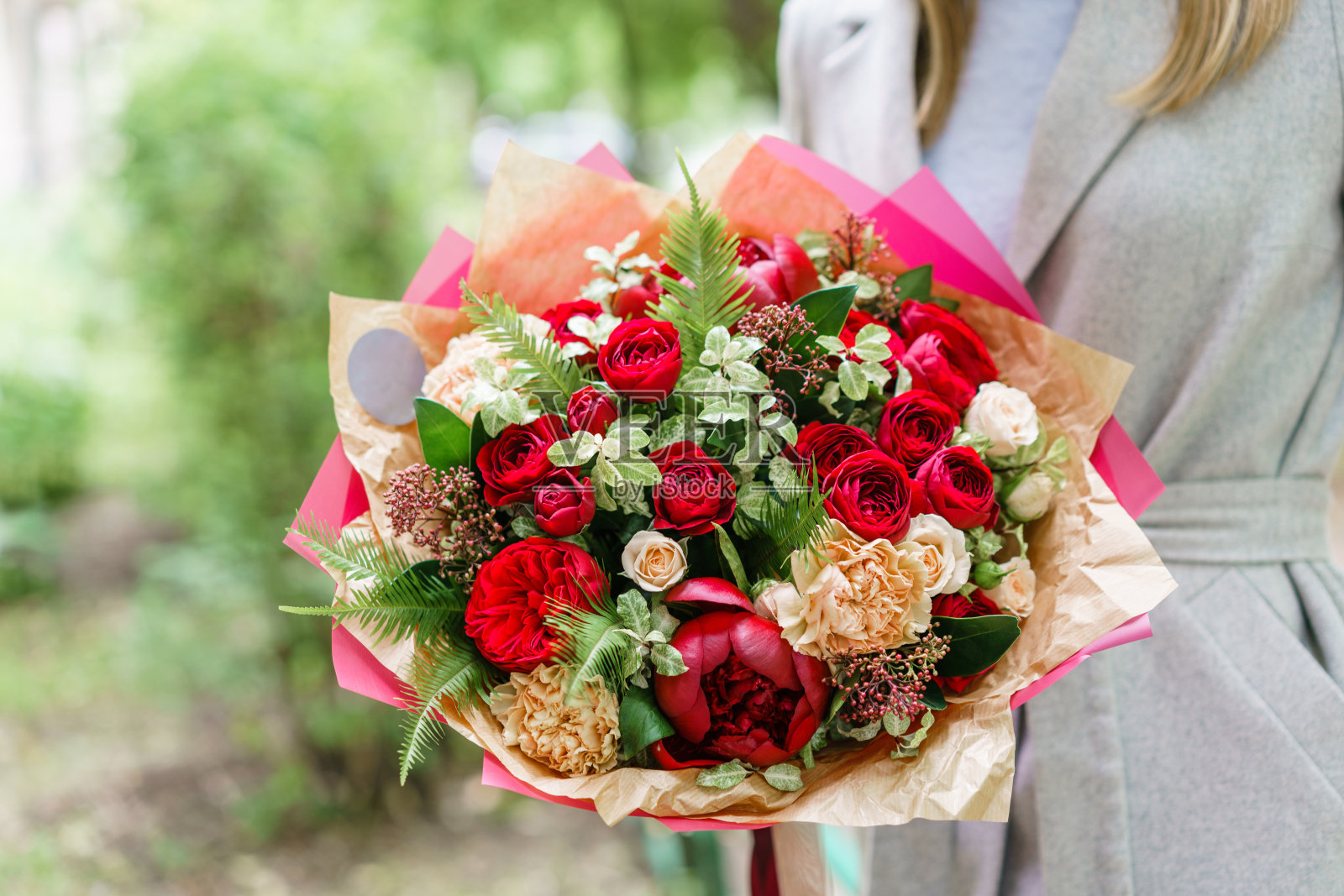 年轻的女孩拿着美丽的春天的花束。插花与红牡丹。花店的概念，一个小型家庭企业照片摄影图片