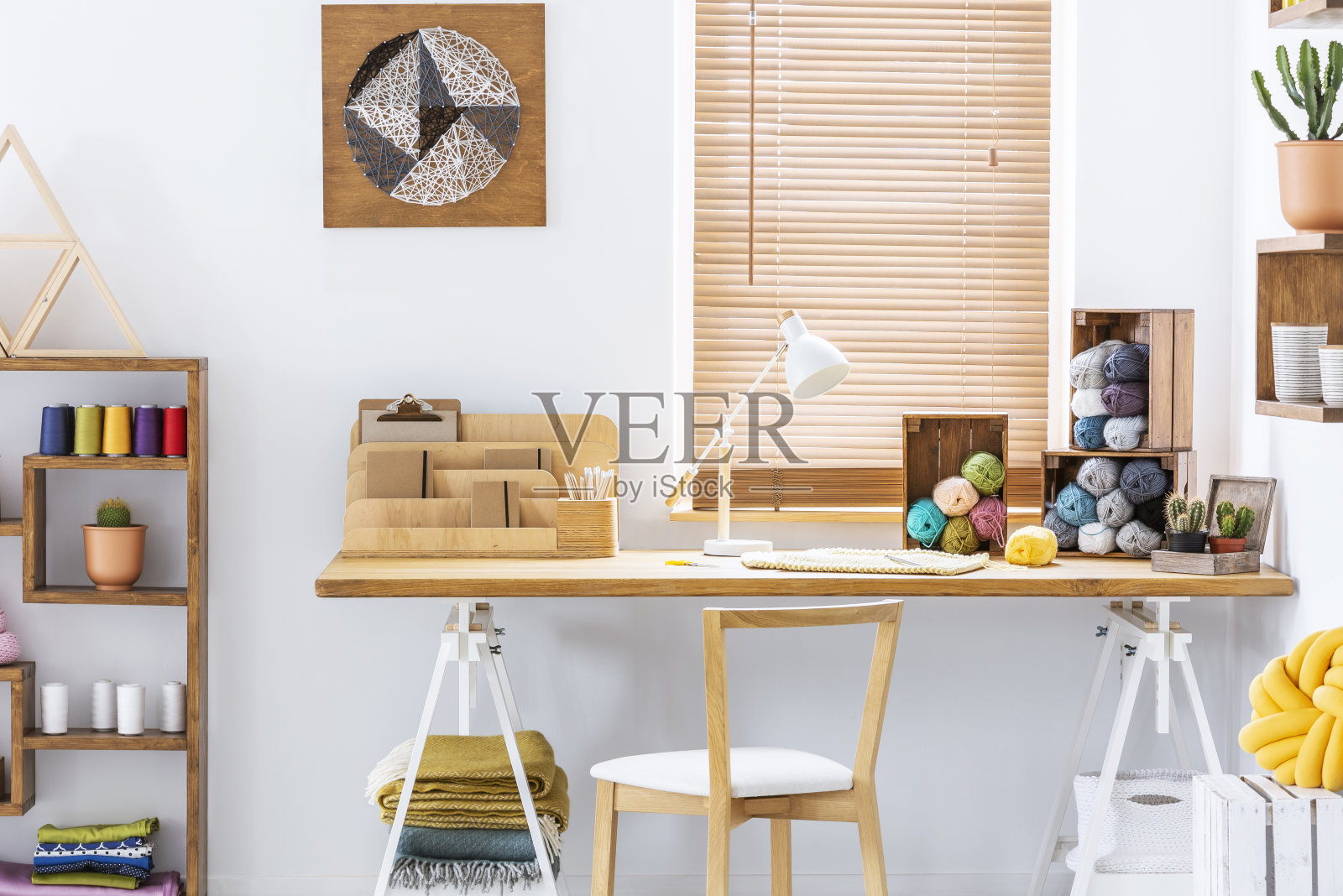 木制椅子在书桌与灯和彩色纱线在家庭办公室内部与海报。真实的照片照片摄影图片