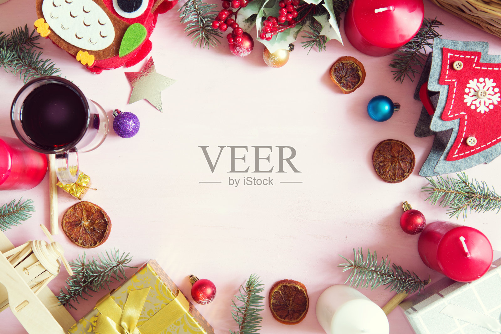 圣诞框架或边框上有大量的圣诞道具，装饰品，球，礼物和蜡烛在一个粉红色的木制背景松树枝和copyspace，俯瞰照片摄影图片