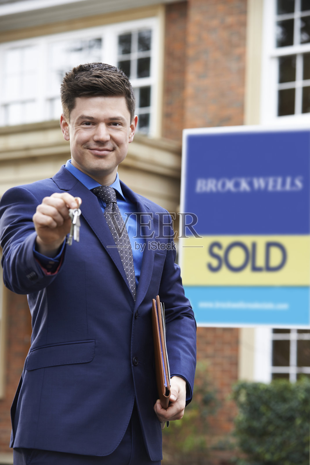 男房地产经纪人拿着钥匙站在住宅物业外的肖像照片摄影图片