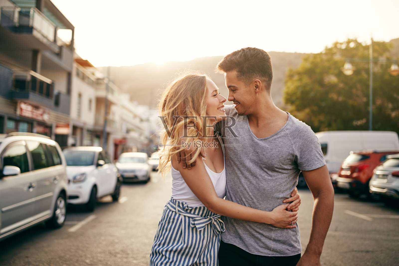 微笑的年轻夫妇拥抱着走在城市的街道上照片摄影图片
