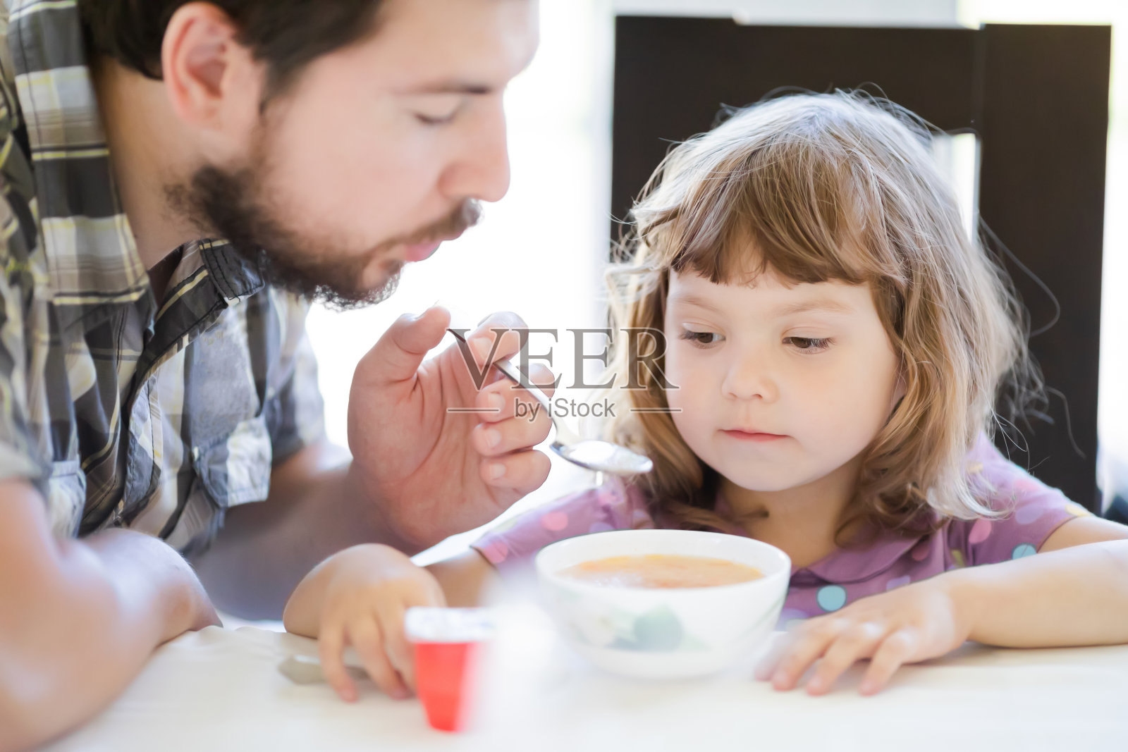 年轻的父亲喂养他的小女儿，父亲的身份照片摄影图片