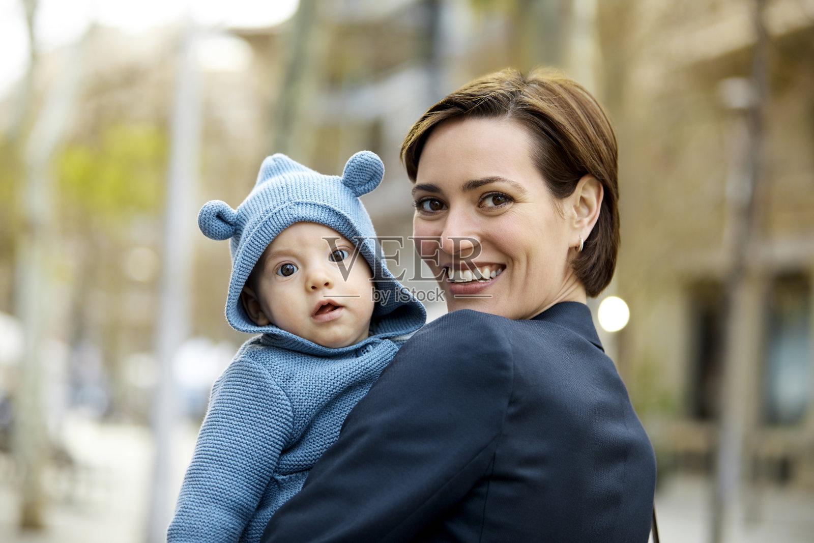 满面笑容的母亲在城市里抱着儿子照片摄影图片