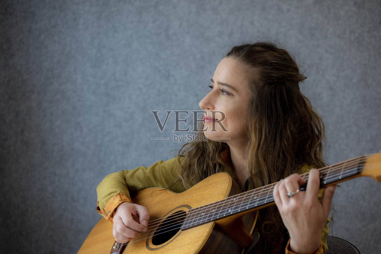 年轻女子在弹吉他。照片摄影图片