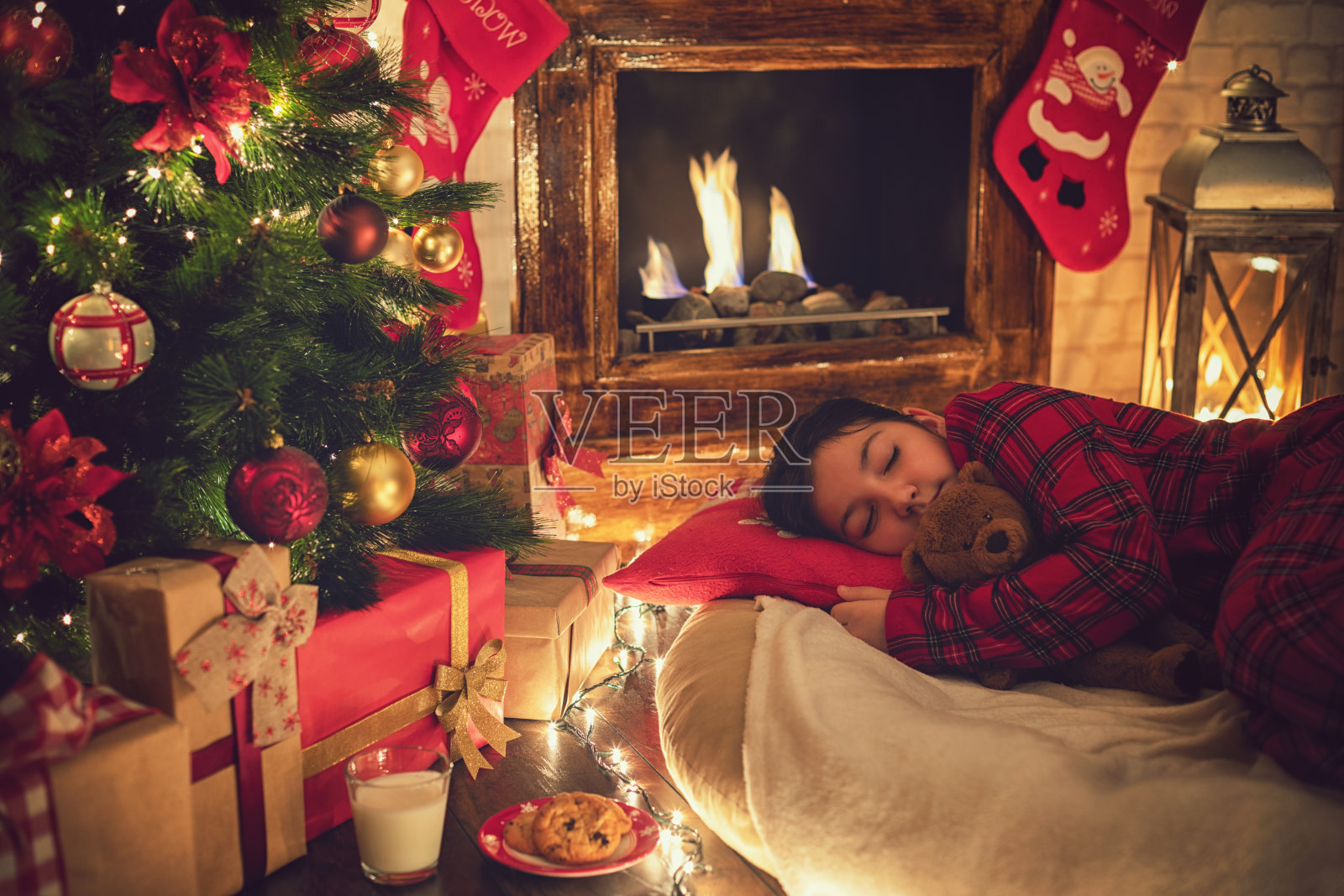 圣诞节前夕，穿着睡衣的小女孩在圣诞树旁睡着了照片摄影图片