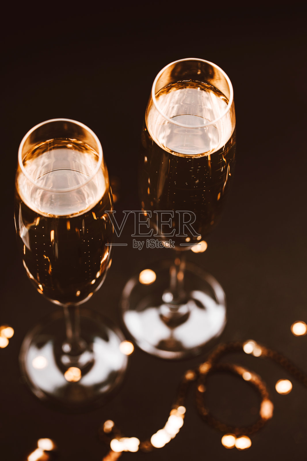 两杯香槟装饰在黑色优雅的背景上。照片摄影图片