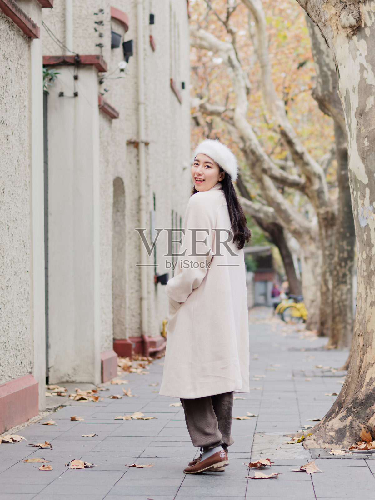 在秋天的城市里，穿着白色绒毛外套的漂亮年轻女子。户外时尚写真魅力中国开朗时尚的街头淑女。情感、人、美、生活理念。照片摄影图片