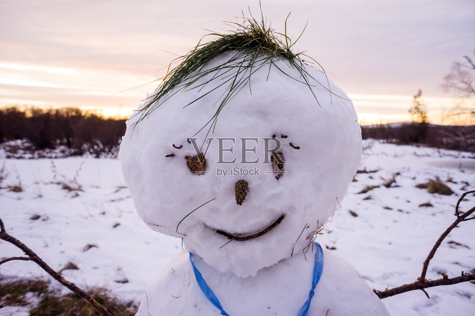 一个雪人的头特写是在黄昏的日落微笑。照片摄影图片