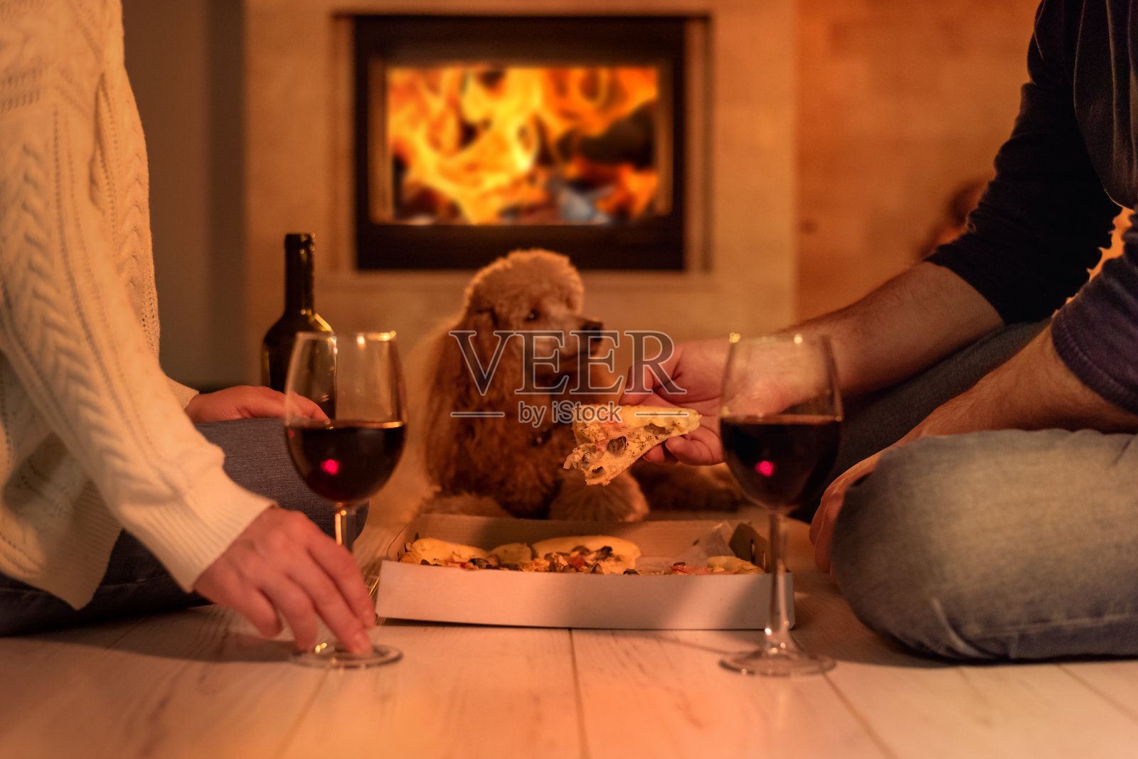 年轻的夫妇有浪漫的晚餐，披萨和葡萄酒在壁炉的背景。照片摄影图片