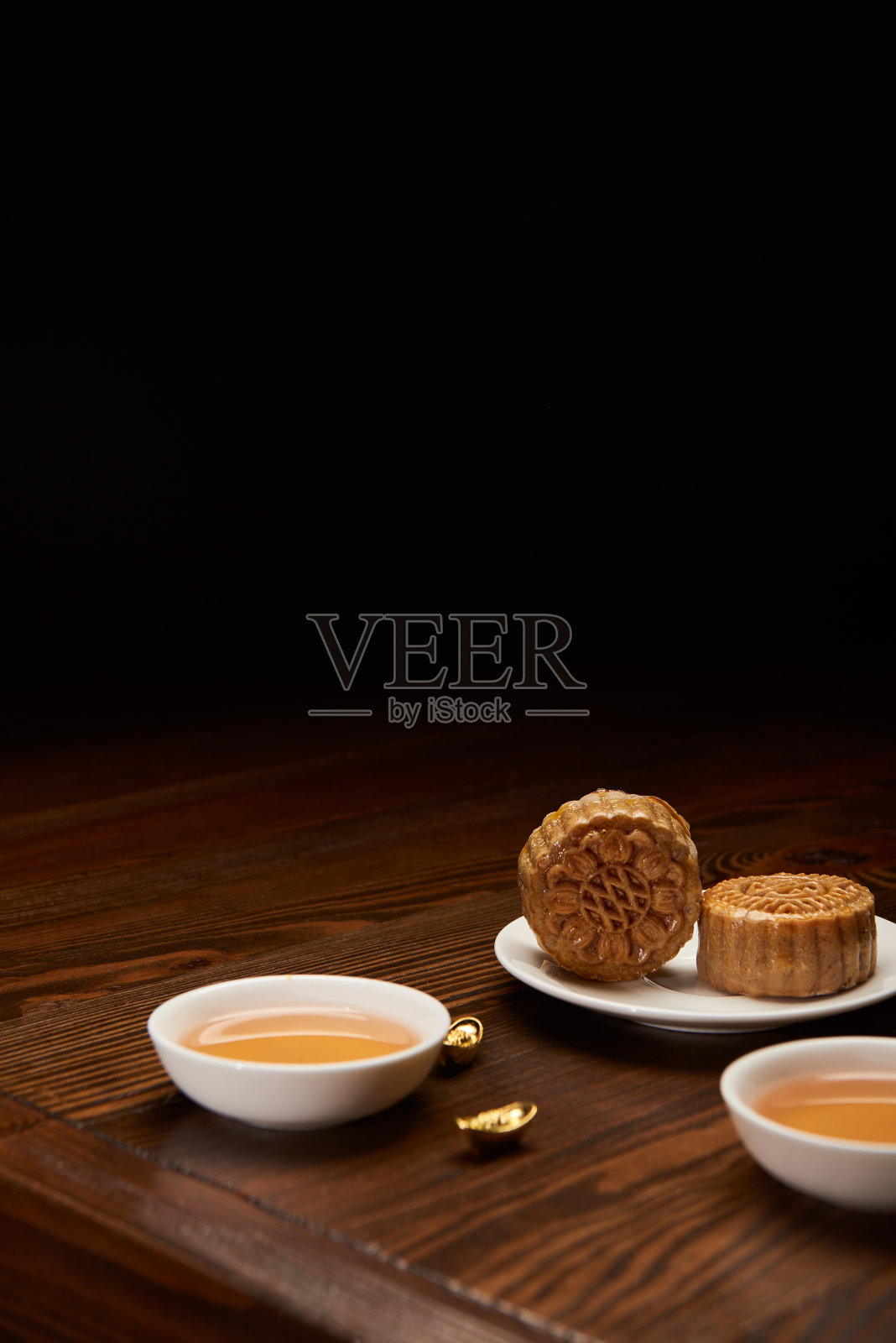 传统月饼用茶杯和金元宝孤立在黑色与复制空间照片摄影图片