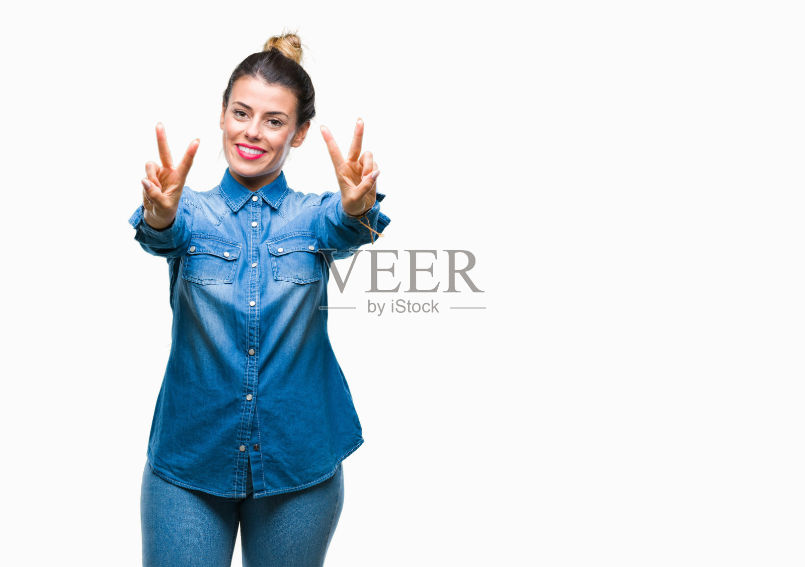 年轻美丽的女人在孤立的背景微笑看着相机显示手指做胜利的手势。二号人物。照片摄影图片