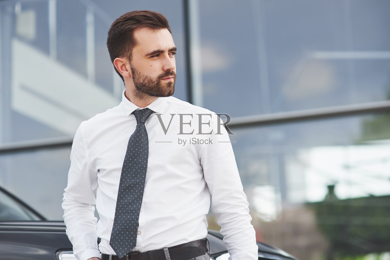 一个穿着职业装的漂亮男人站在办公室外面的肖像。照片摄影图片
