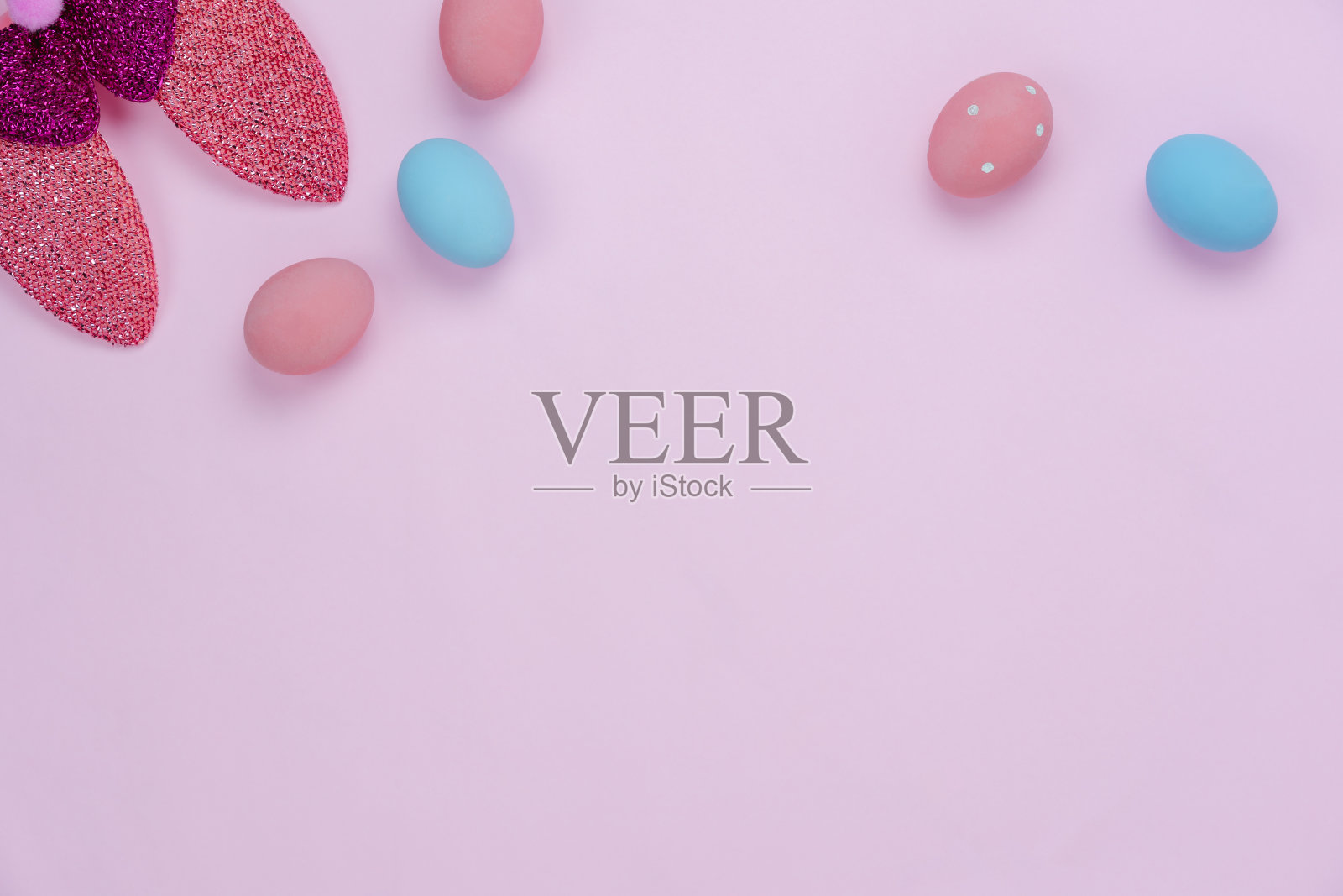桌面视图拍摄的装饰复活节节日快乐的背景概念。在现代乡村的粉红色纸上，平生着五颜六色的蛋和可爱的兔子耳朵。空白空间的创意设计模型和模板。照片摄影图片