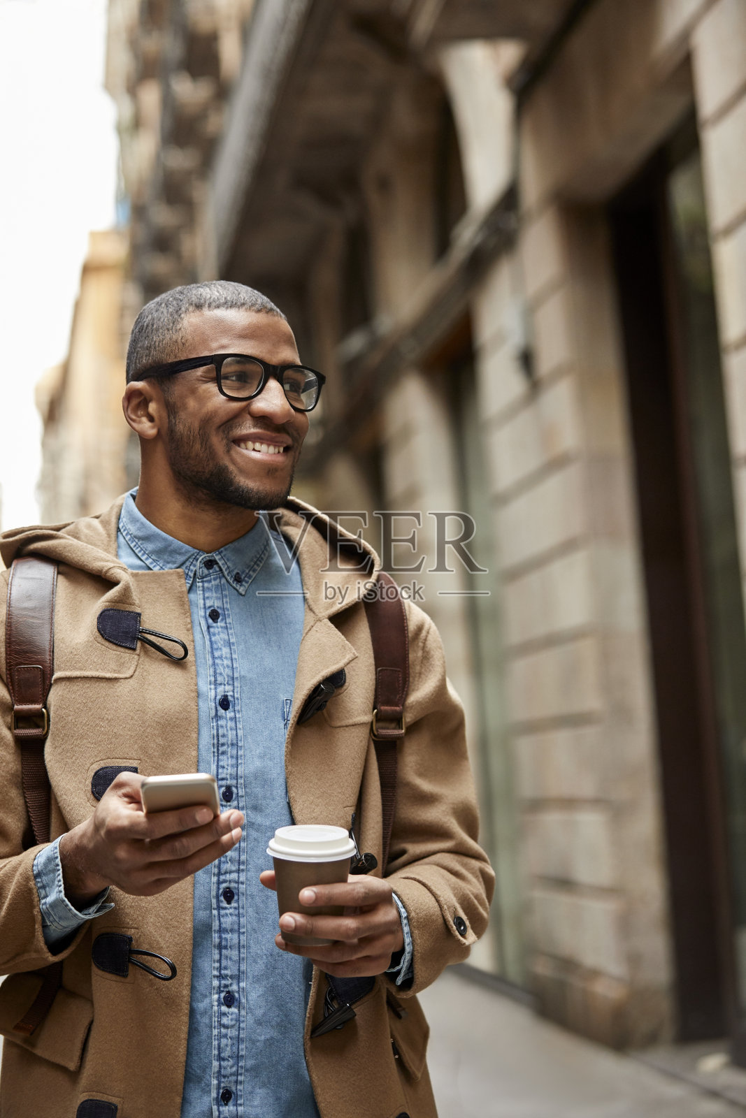 微笑的男人拿着一次性杯子和智能手机照片摄影图片