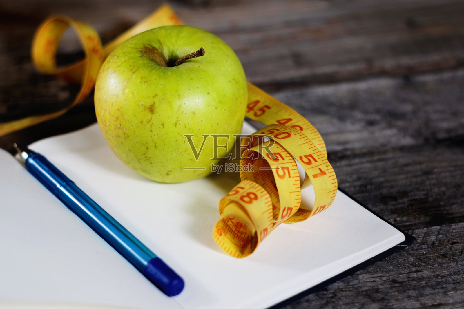 饮食计划，空笔记本，铅笔，青苹果和卷尺，平铺在木背景上。照片摄影图片