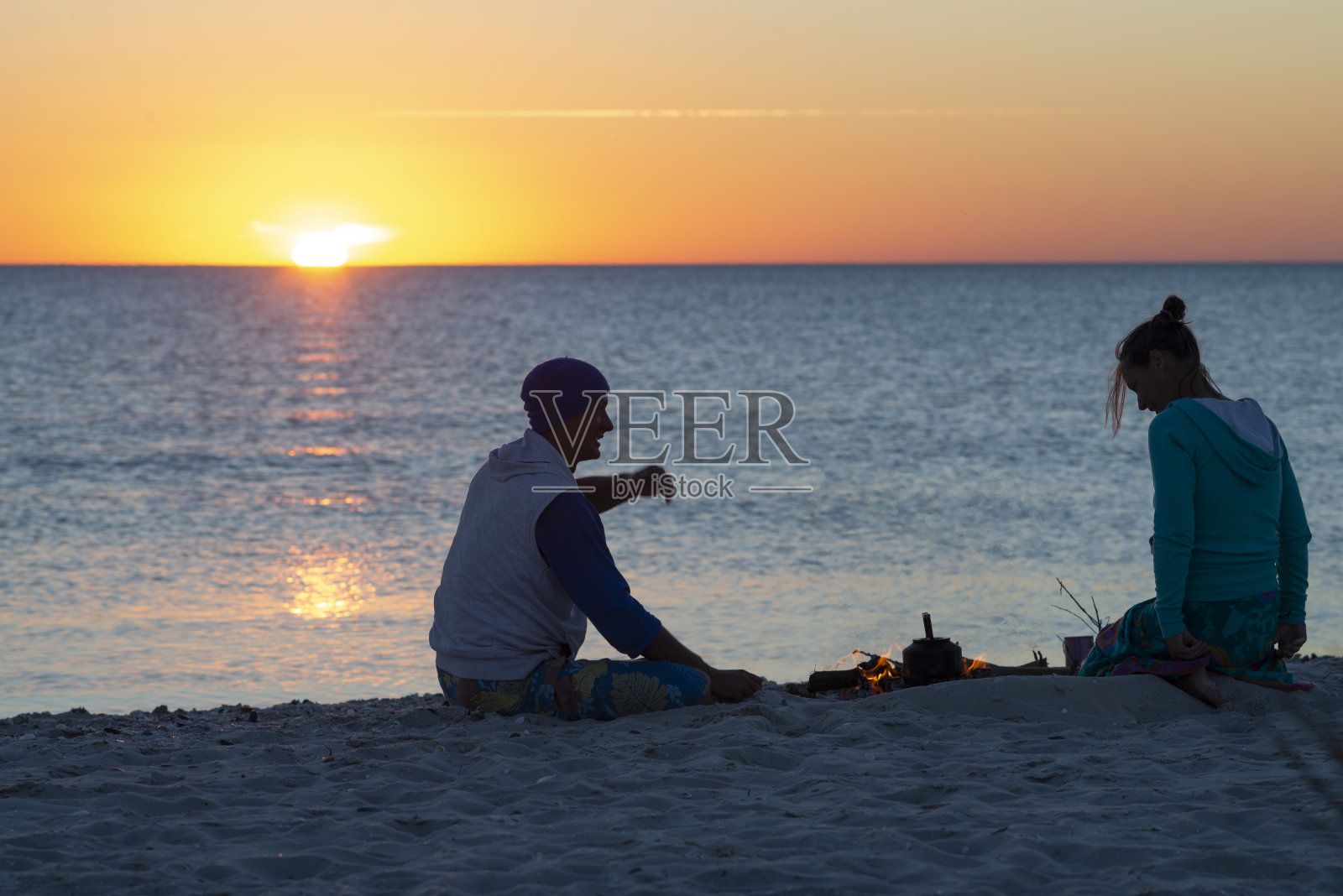 一对浪漫的情侣在海滩上放松，煮着咖啡照片摄影图片