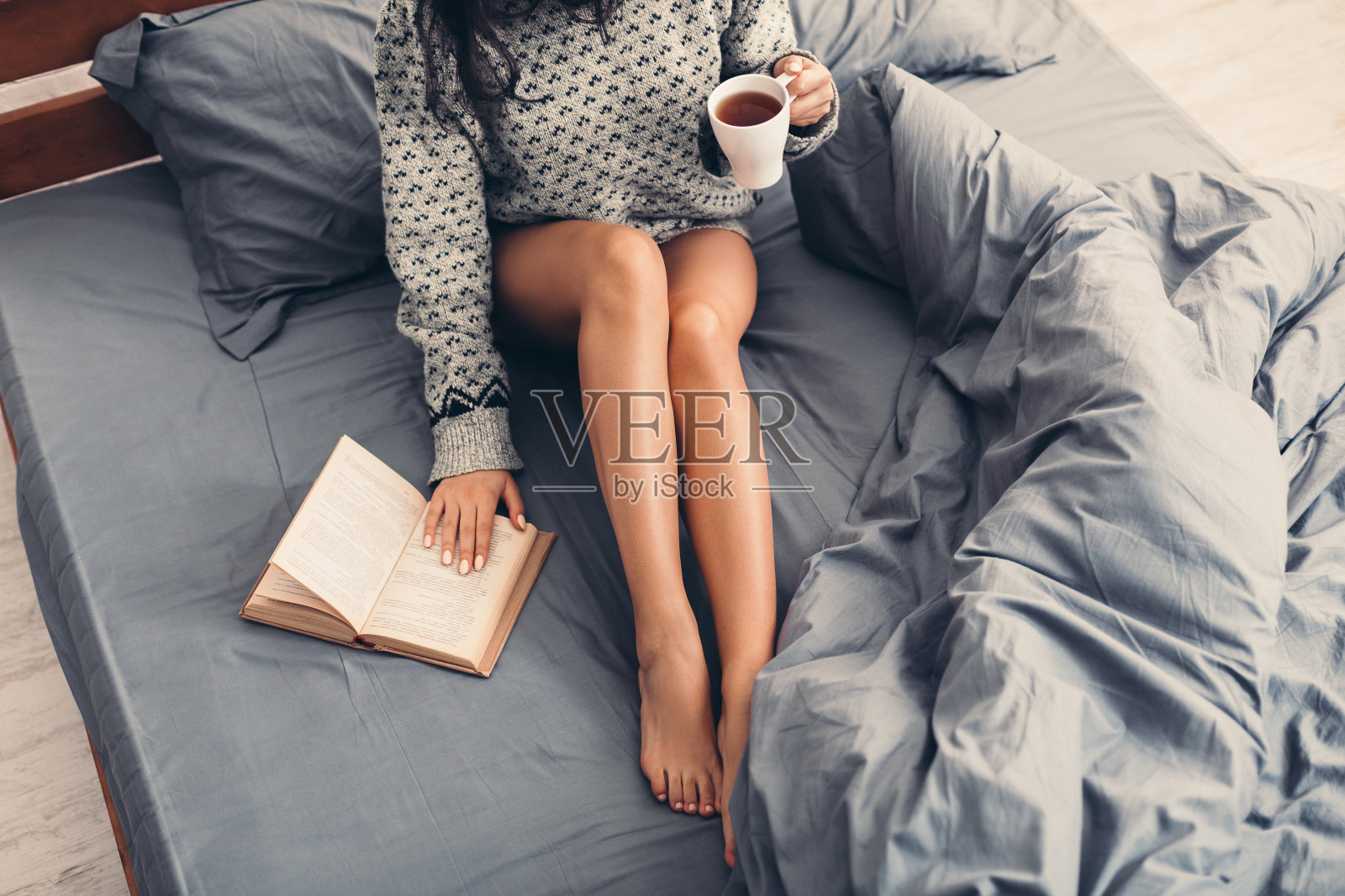 女人躺在床上，拿着书和咖啡照片摄影图片