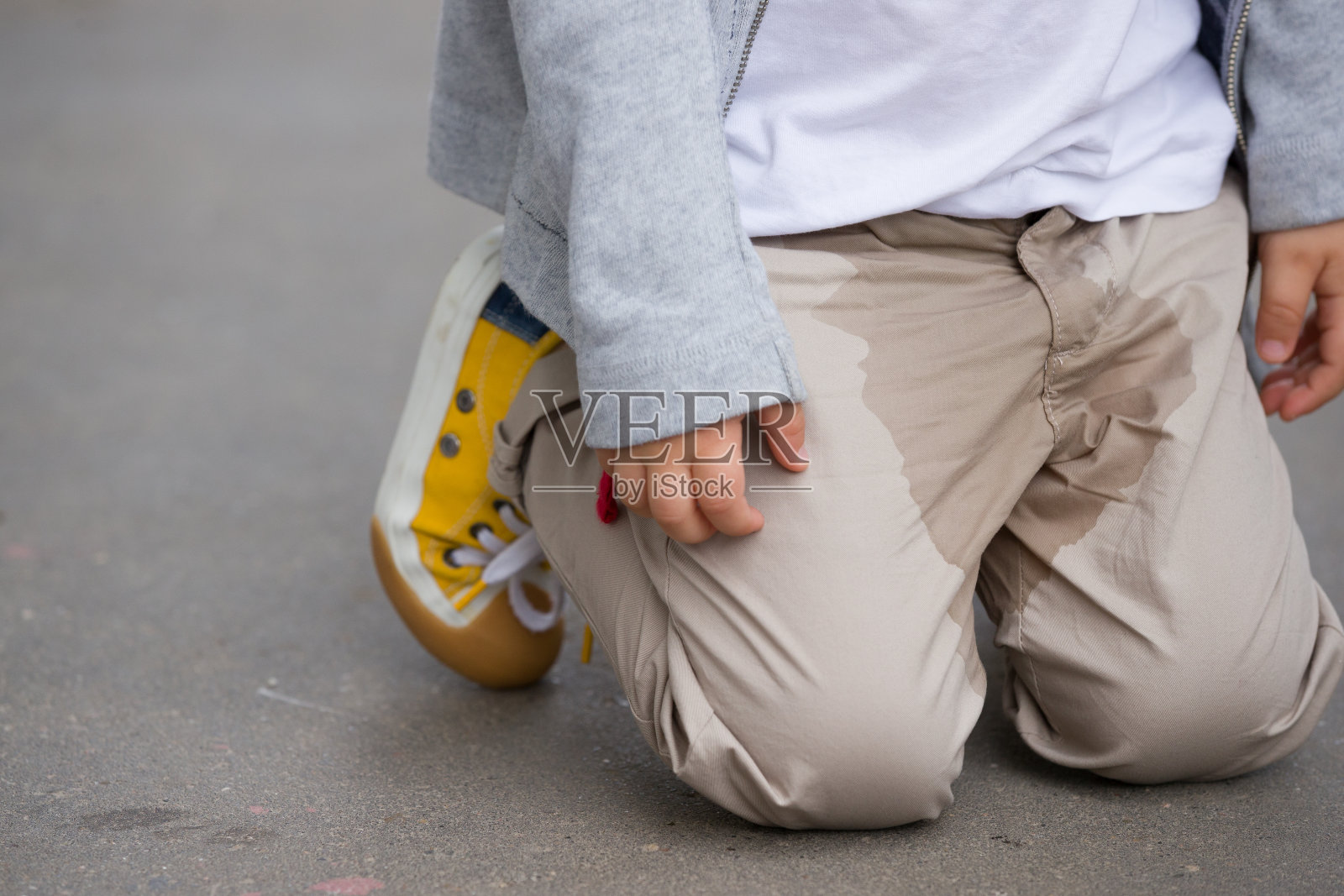 一个小孩在街上尿在裤子上-尿床的概念。孩子尿在衣服上。照片摄影图片