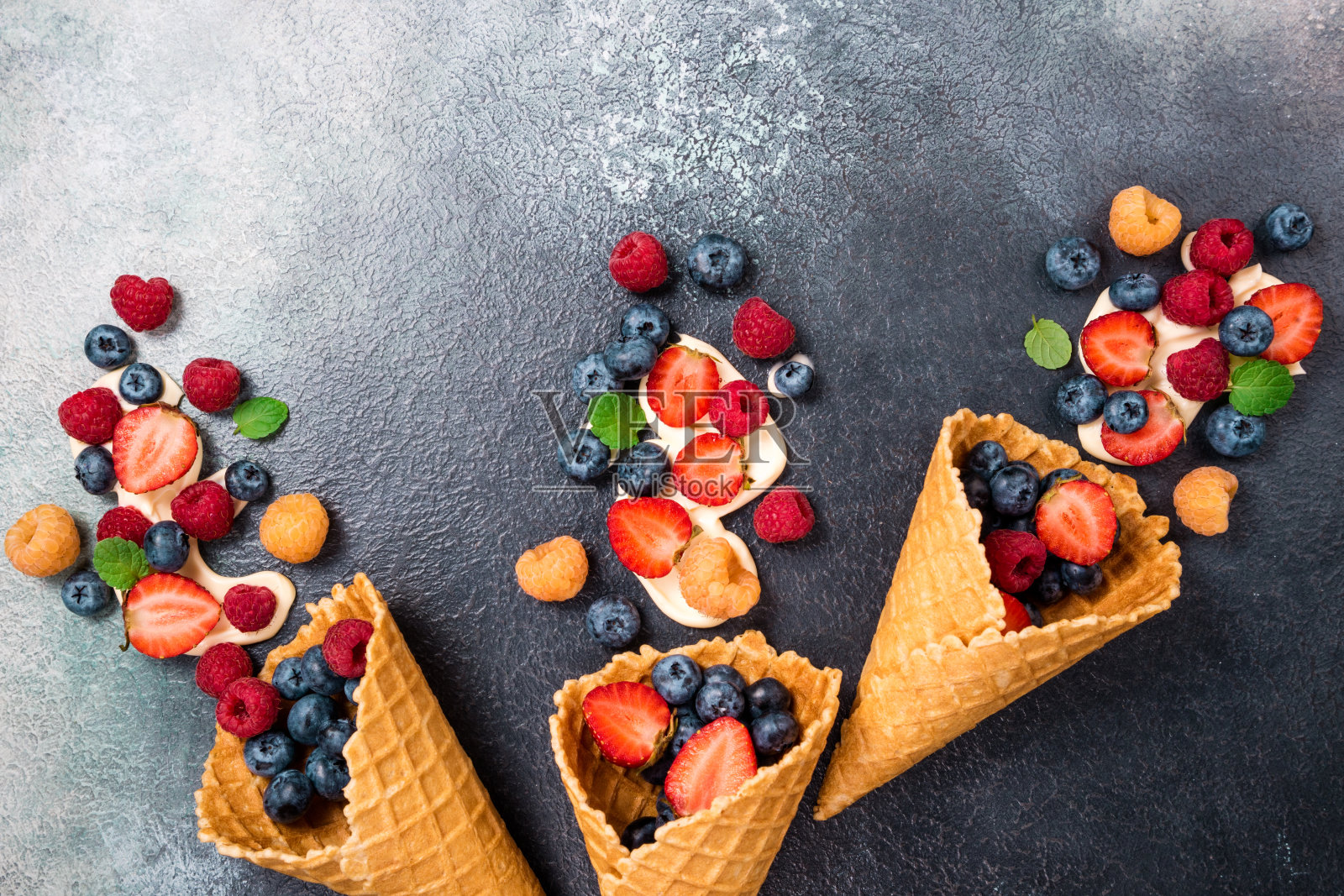 新鲜浆果和冰淇淋蛋卷里的奶油。甜点是草莓、覆盆子、蓝莓。健康饮食、节食食品和营养的概念。夏天的背景照片摄影图片