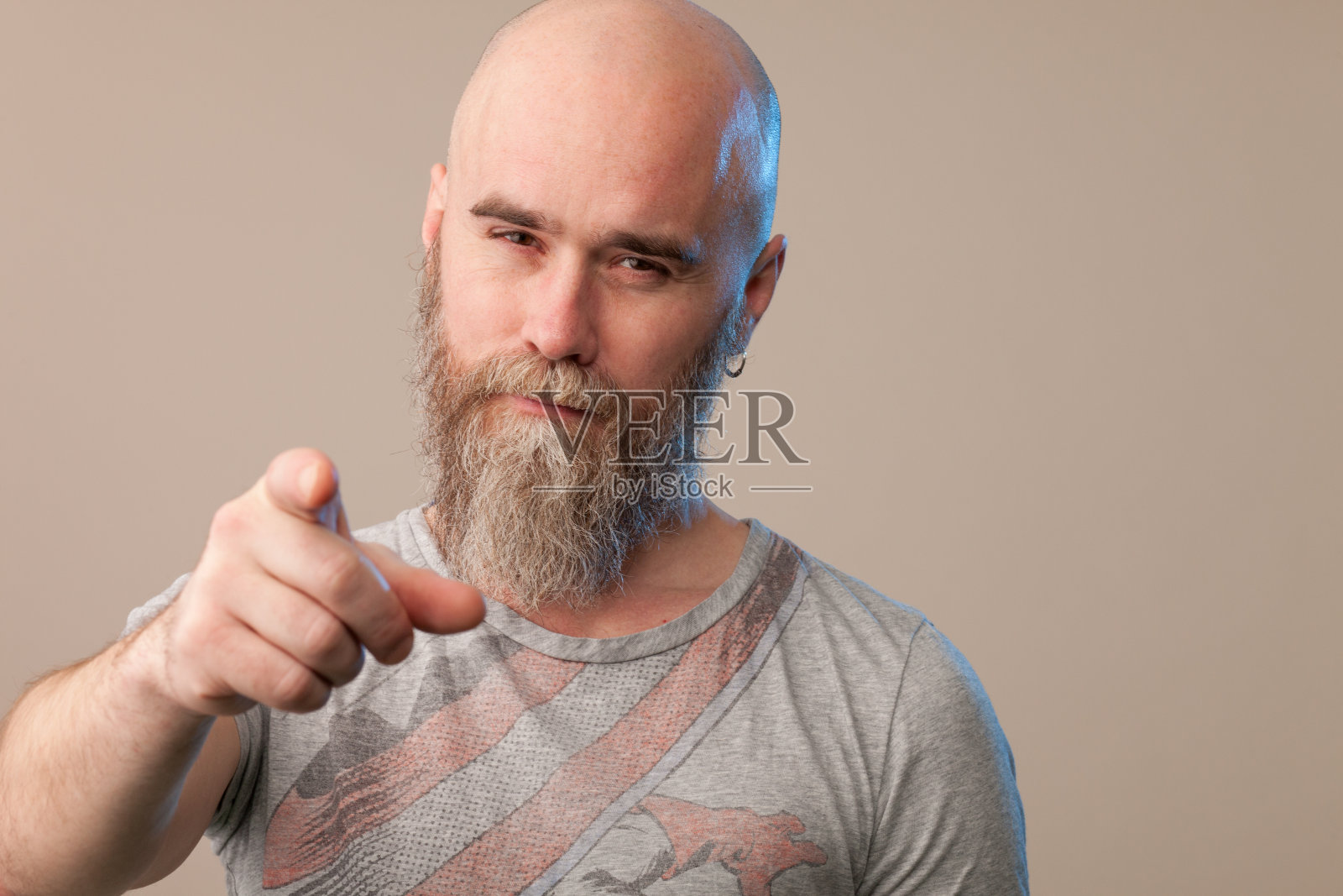 一名40岁剃着光头的大胡子男子的工作室肖像，他穿着一件米色背景的t恤照片摄影图片