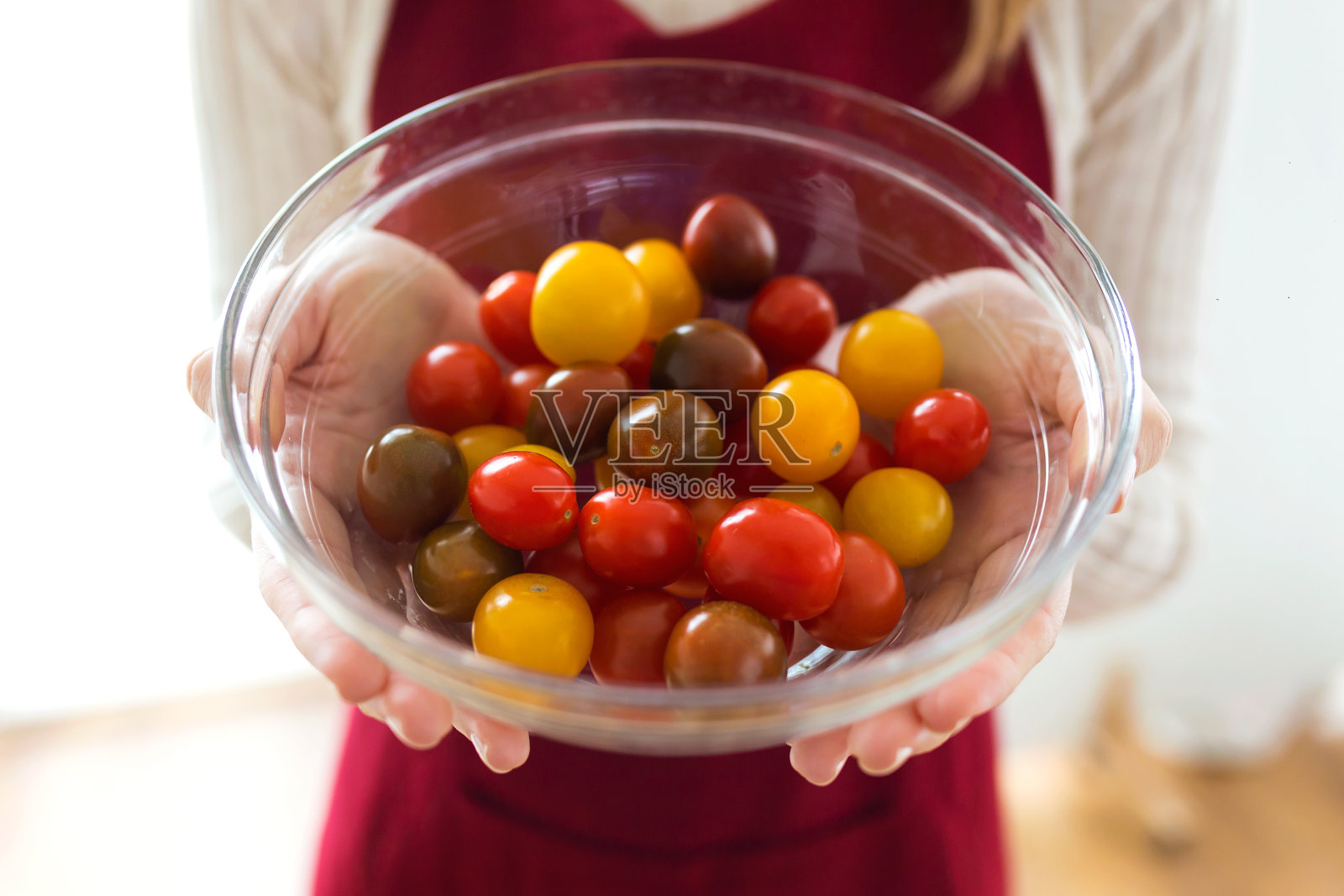 妇女手捧不同类型的樱桃番茄在圆碗里在家。照片摄影图片