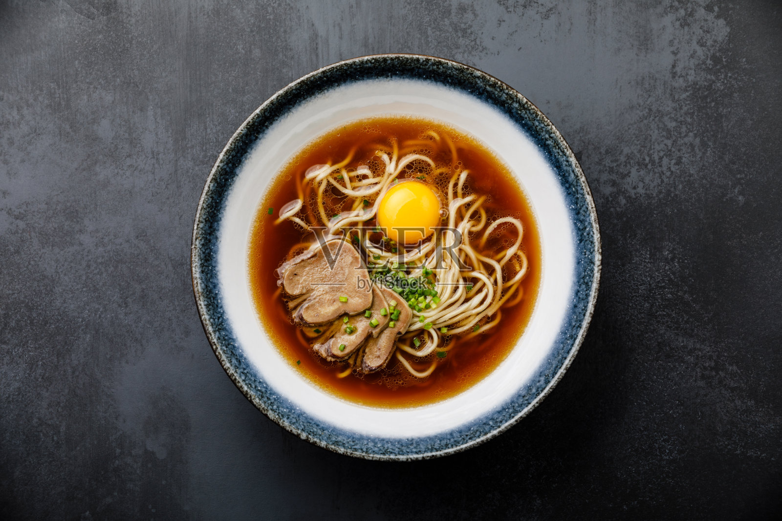 亚洲拉面，牛肉舌肉和生蛋黄在碗里，黑色背景照片摄影图片