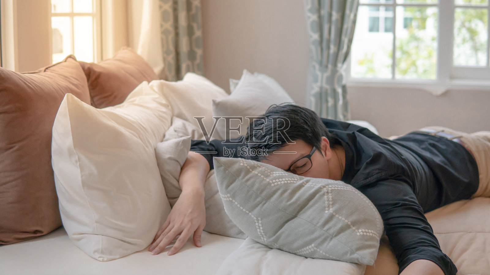 年轻的亚洲男人戴着眼镜，早上睡在卧室的床上。家居生活方式概念照片摄影图片