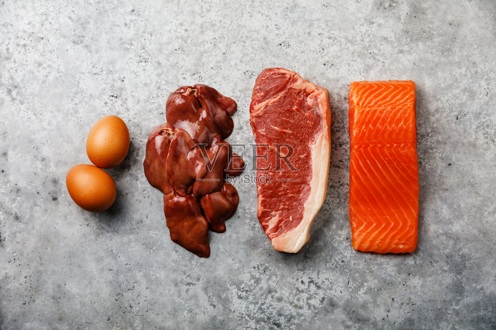 生酮饮食生食选择鸡蛋，鸡肝，牛肉牛排和鲑鱼排在灰色混凝土背景照片摄影图片