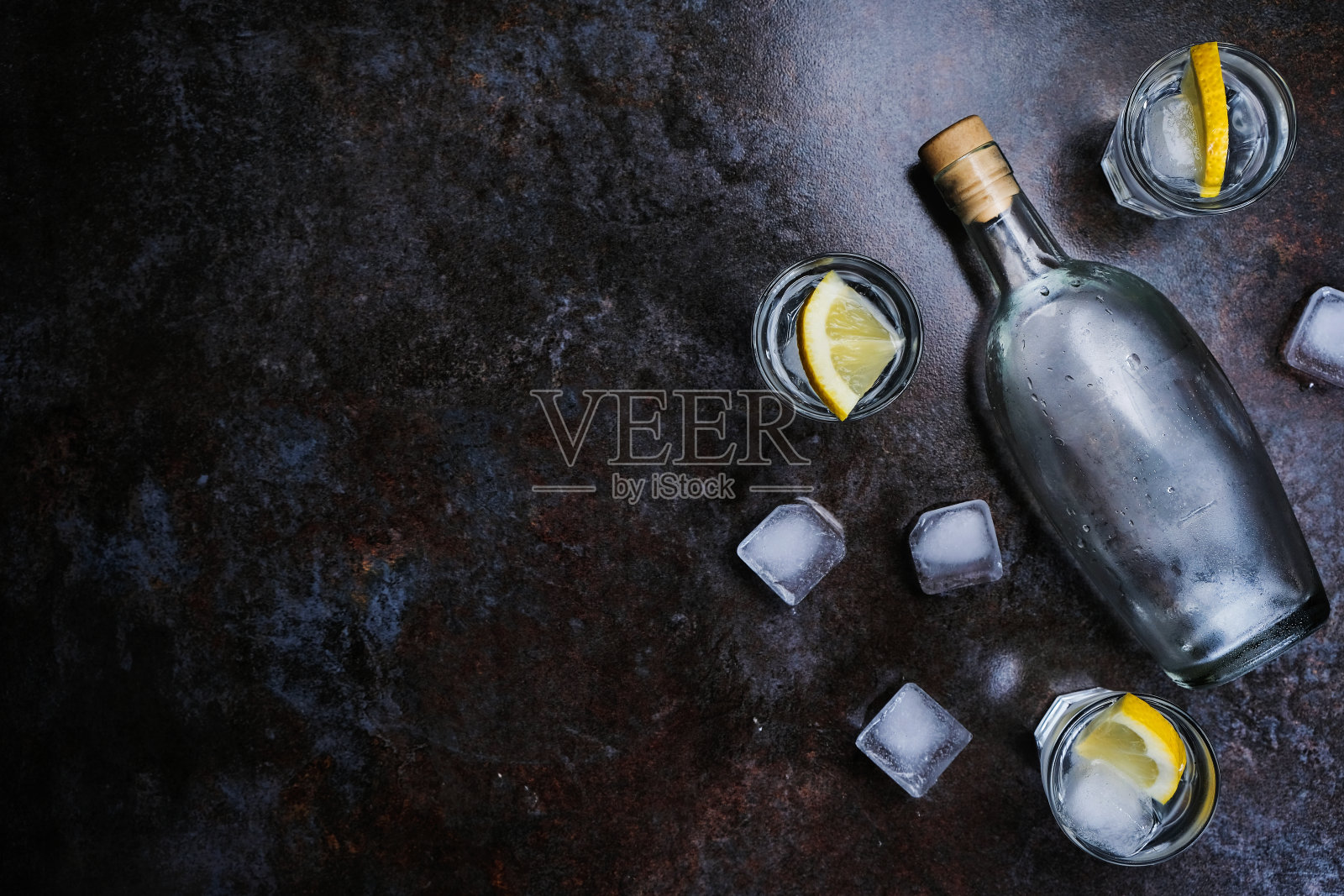 冰伏特加在小酒杯与柠檬石背景。俯视图，复制空间。照片摄影图片