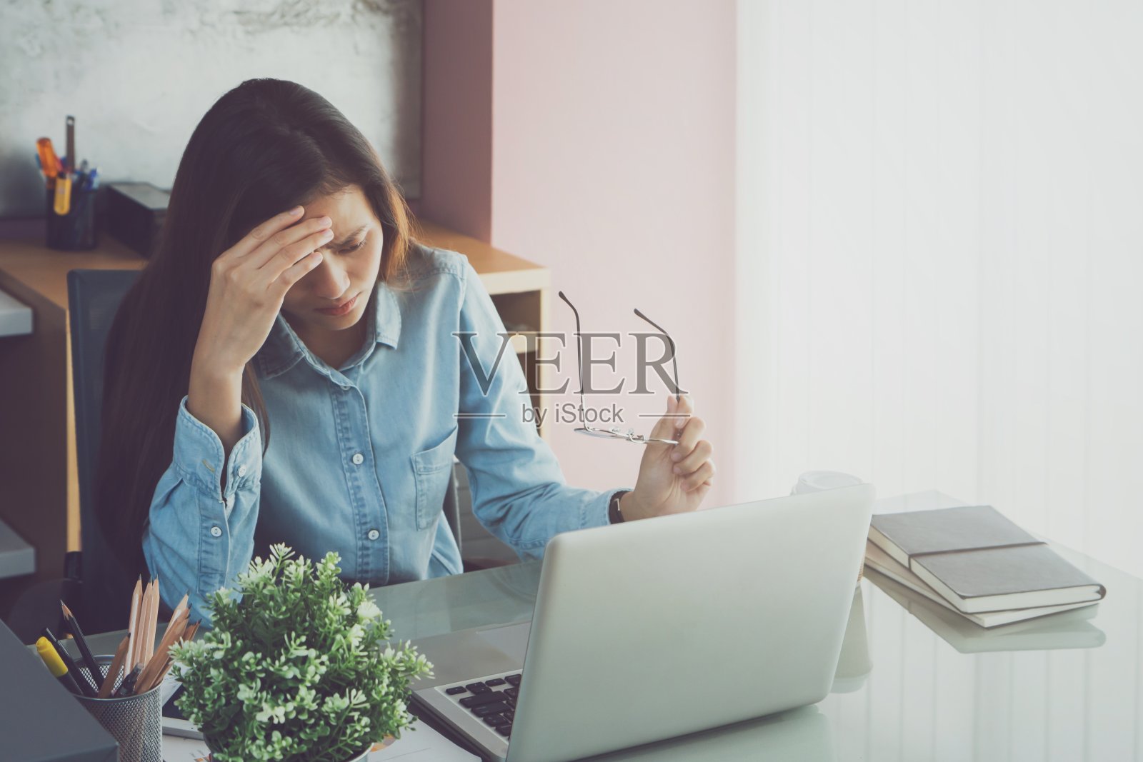 亚洲美女长时间使用笔记本电脑工作后会感到压力和头痛。办公室综合症的概念。照片摄影图片
