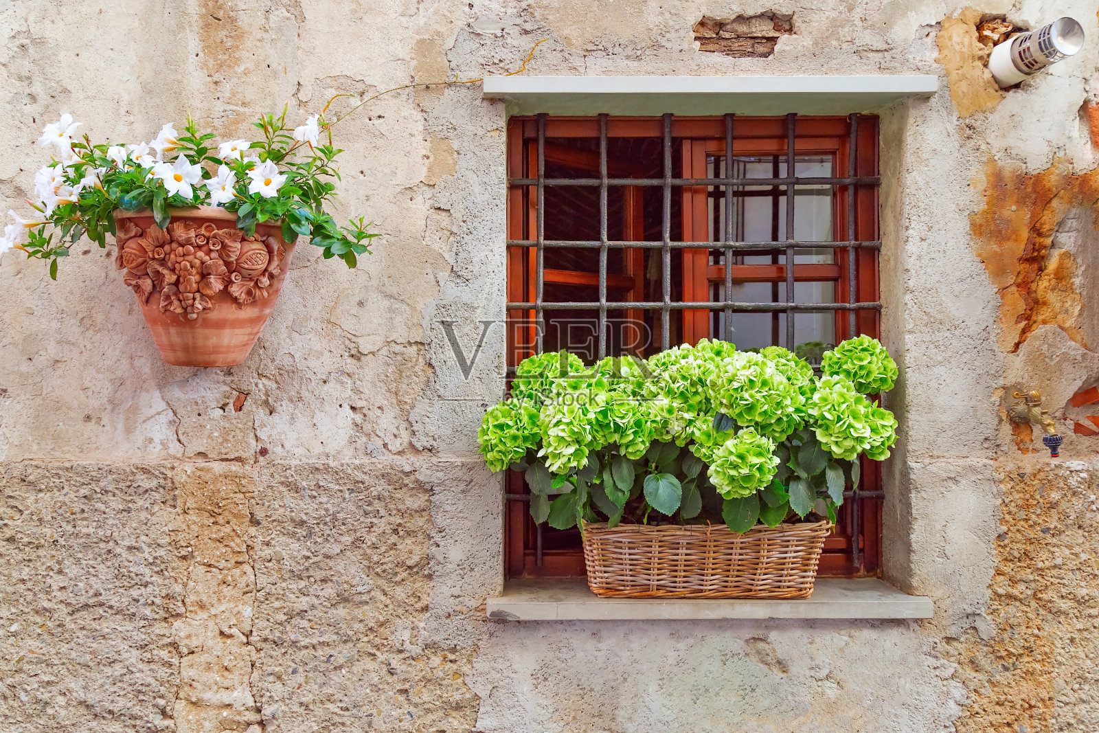意大利小城市萨尔扎纳美丽的老房子墙。北部意大利利古利亚。石墙上舒适的图案。窗户上装饰着鲜花。建筑墙上挂着花的陶罐。照片摄影图片