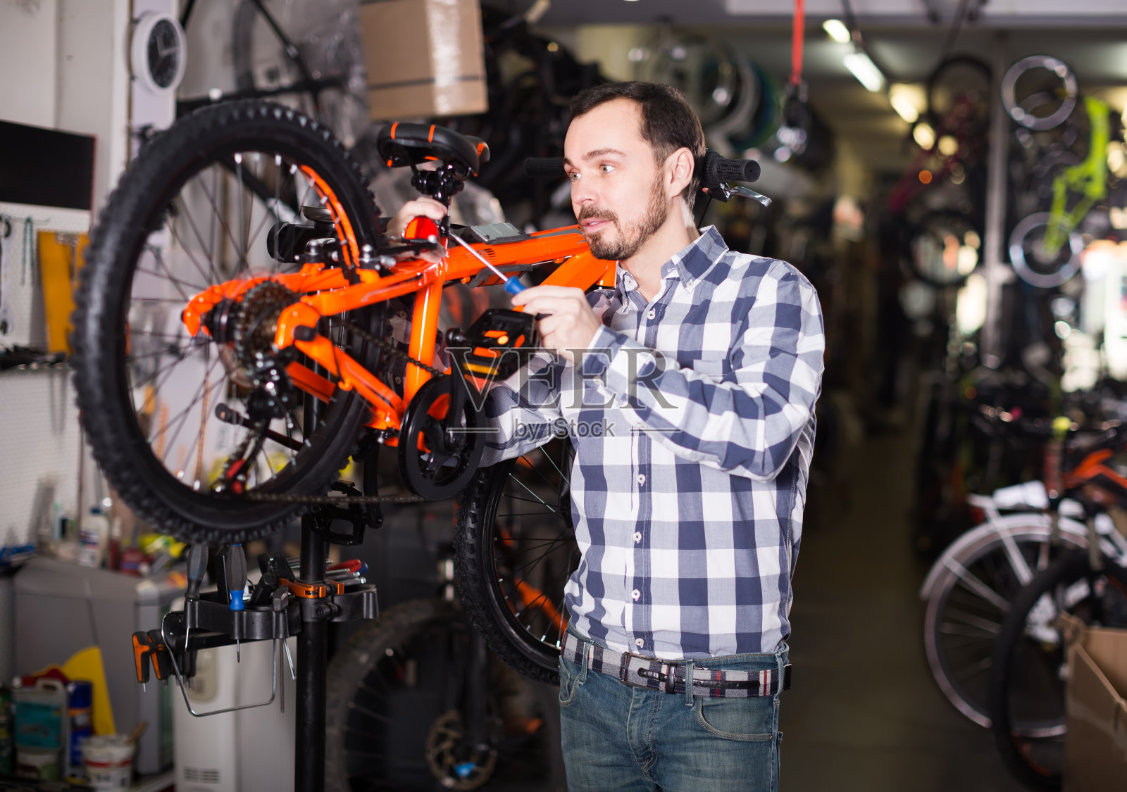 开朗男在商店为组装自行车安装自行车零件照片摄影图片
