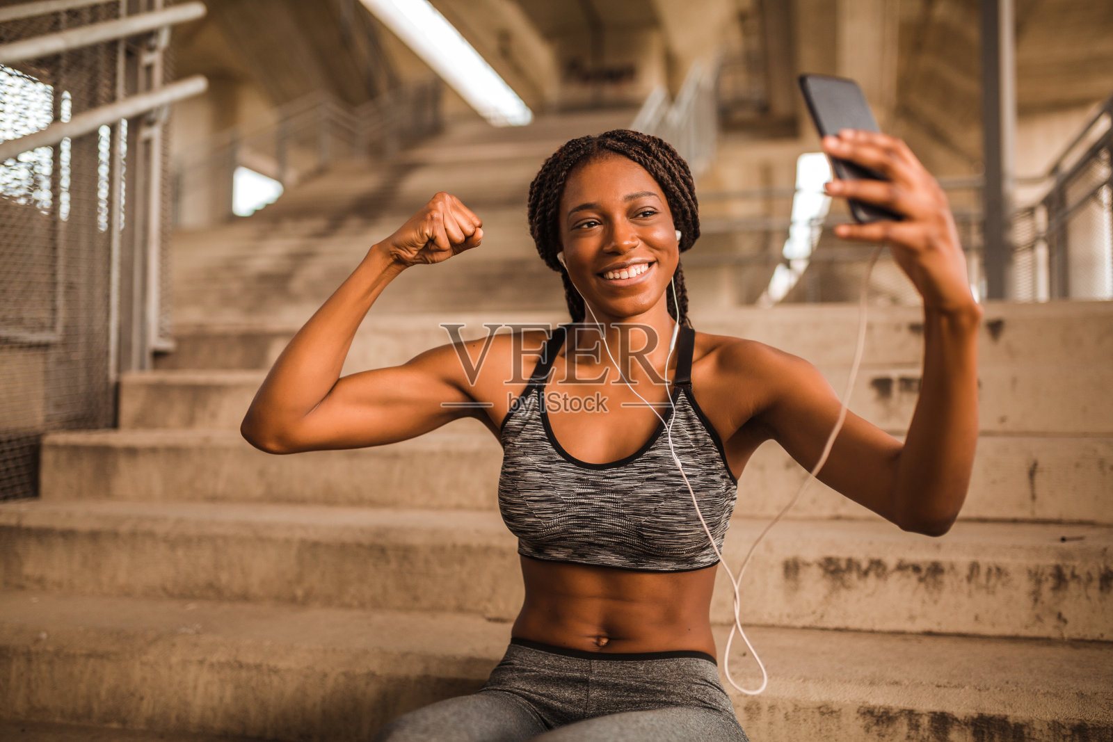 年轻的非洲裔美国女性穿着运动服坐在楼梯上用智能手机自拍照片摄影图片