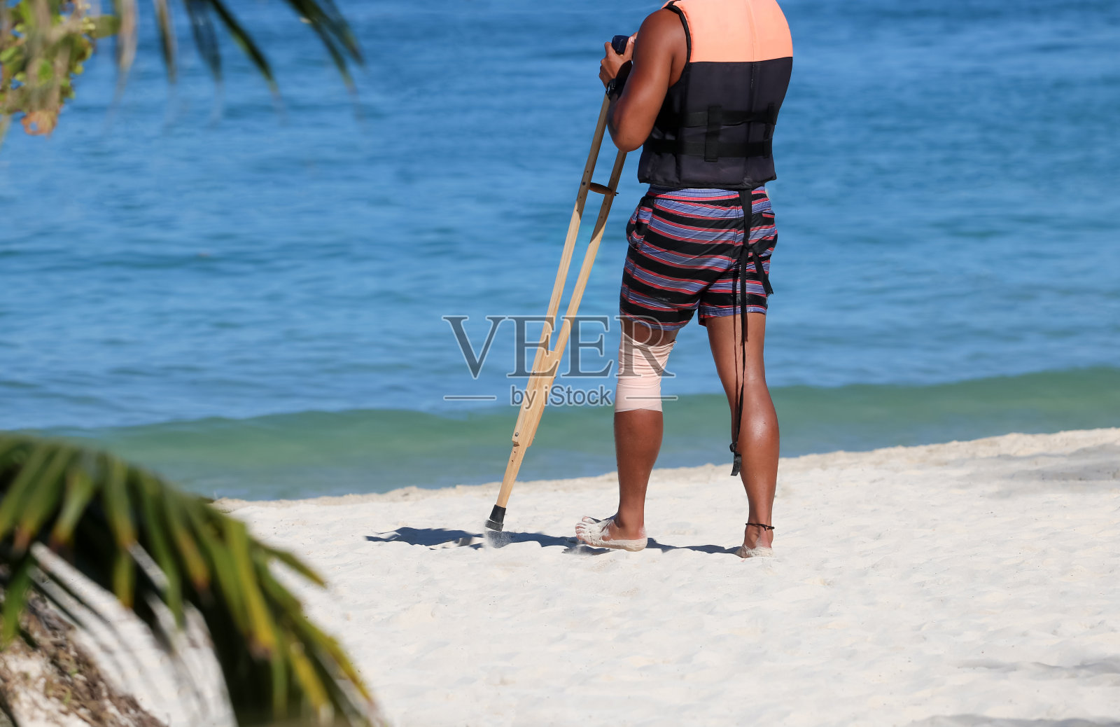 事故游客拄着拐杖在海滩上行走照片摄影图片