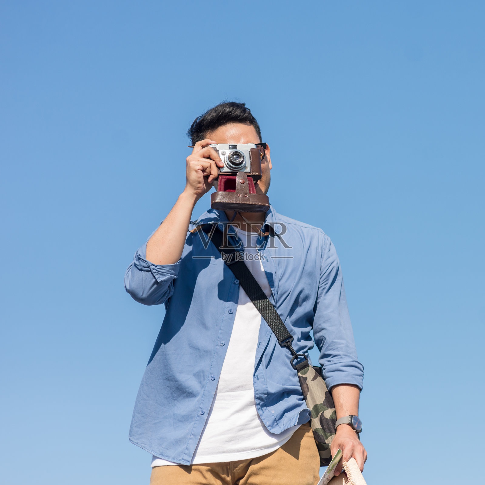 快乐的亚洲游客在阳光明媚的日子里带着复古相机和蓝天。照片摄影图片