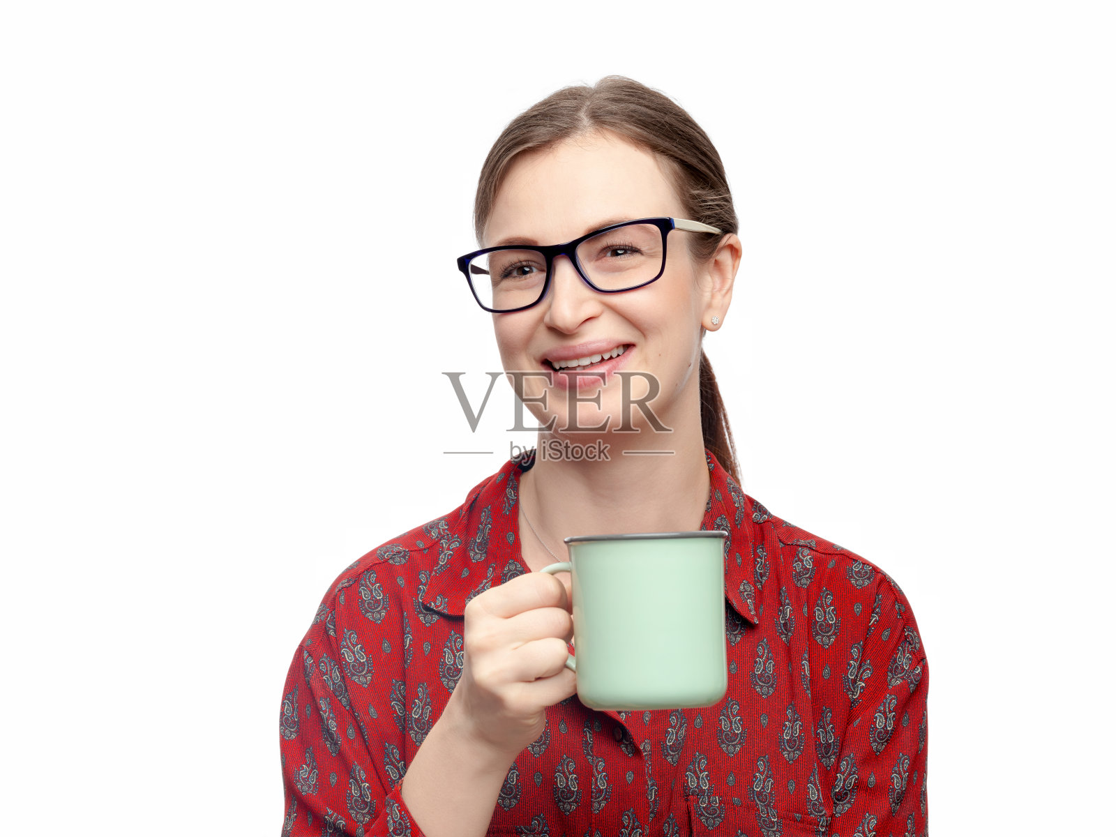 一个漂亮的微笑年轻的黑发女人的肖像与精致的化妆坐在白色的背景。她右手拿着一杯茶或咖啡。水平工作室图像高分辨率。照片摄影图片