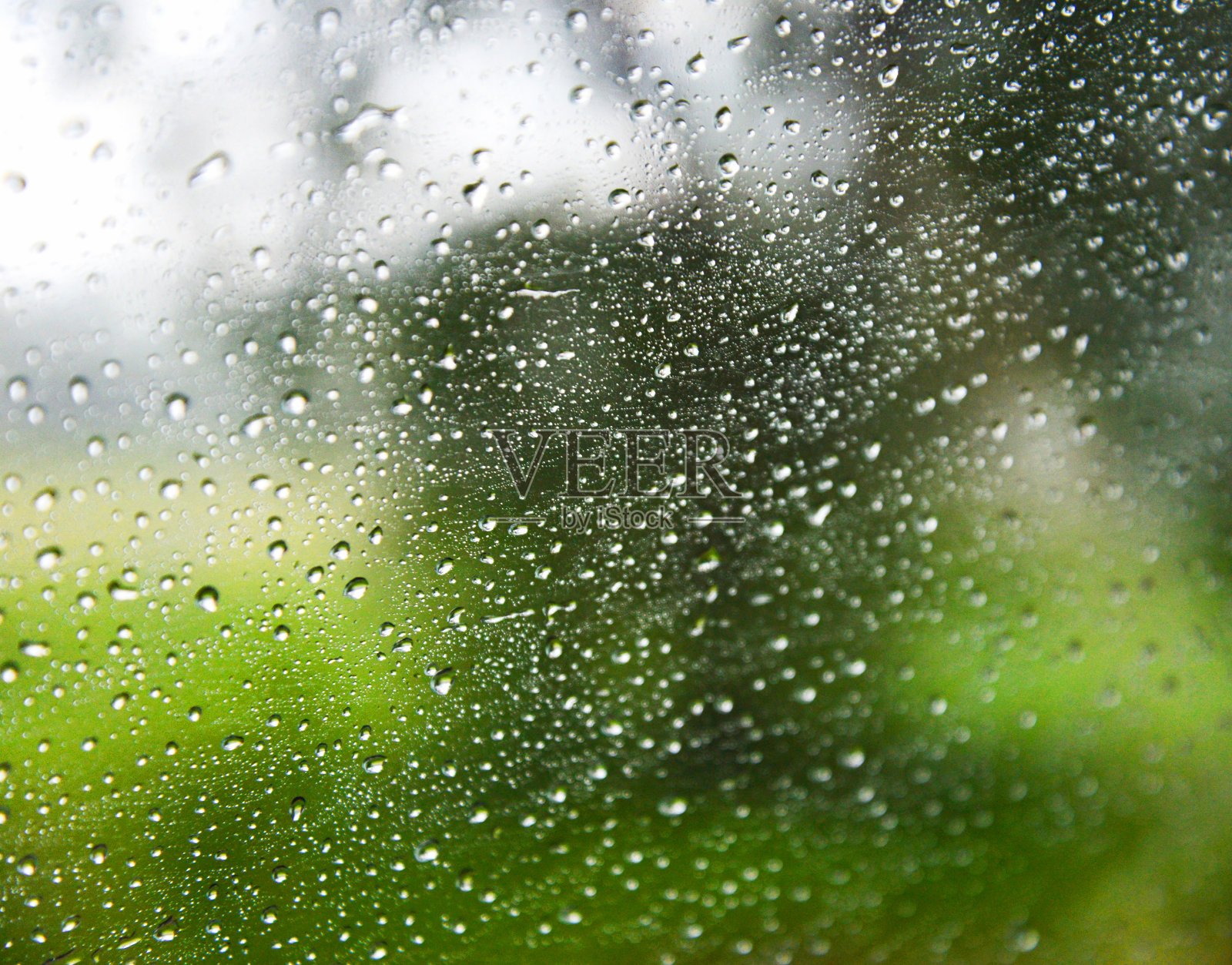 玻璃上的雨滴/雨天窗户玻璃上的水滴和自然模糊了背景照片摄影图片