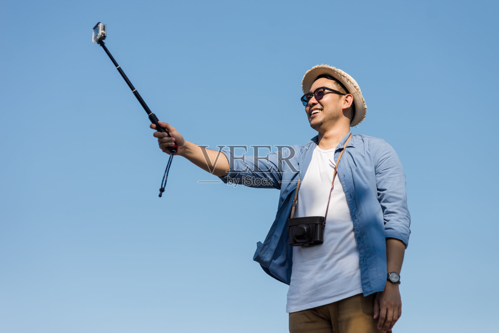 快乐的亚洲游客用相机棒与蓝天合影。照片摄影图片