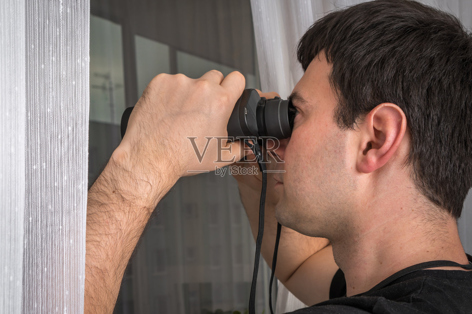 人类正在用双筒望远镜监视他的邻居照片摄影图片