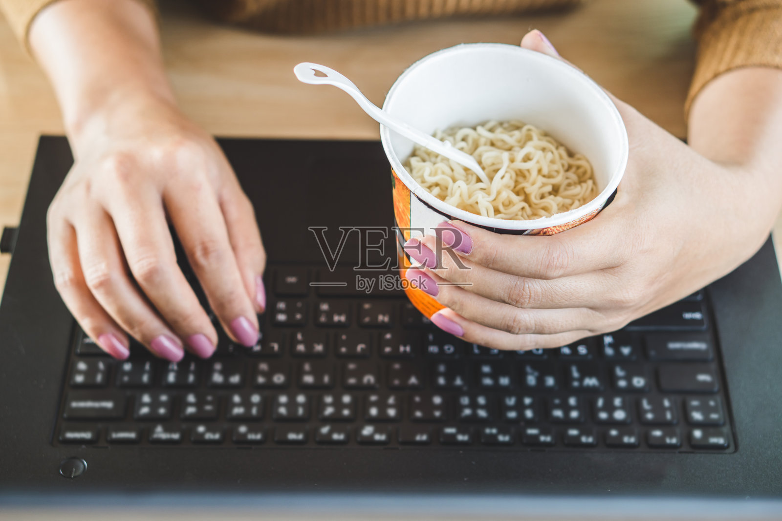 忙碌的商务妇女手吃面条在办公桌上的电脑笔记本电脑照片摄影图片