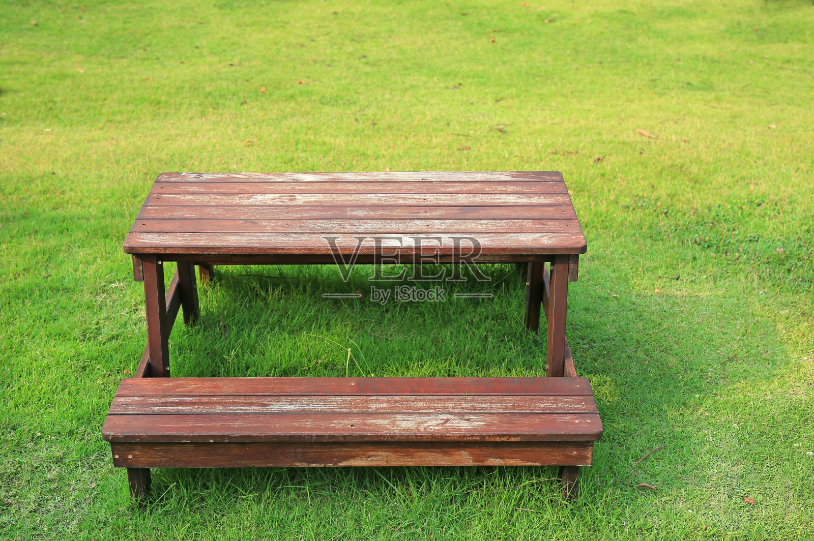 木制桌椅摆放在花园的绿色草坪上。照片摄影图片