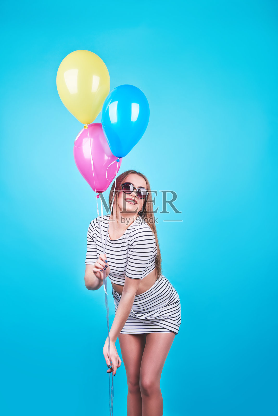 快乐微笑的女人正在看一个空气彩色气球在一个蓝色的背景有乐趣照片摄影图片