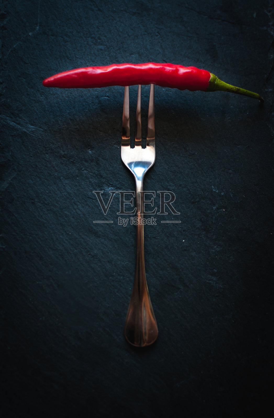 叉子上放辣椒，背景色为黑色照片摄影图片